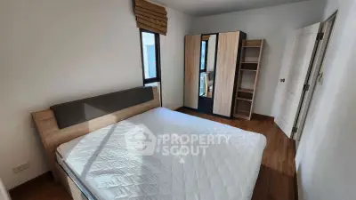 Cozy bedroom with wooden flooring, modern wardrobe, and natural light.
