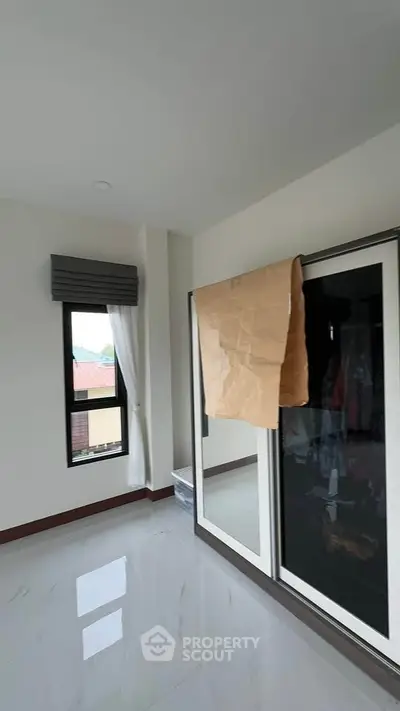 Spacious bedroom with large window and modern wardrobe, perfect for natural light lovers.