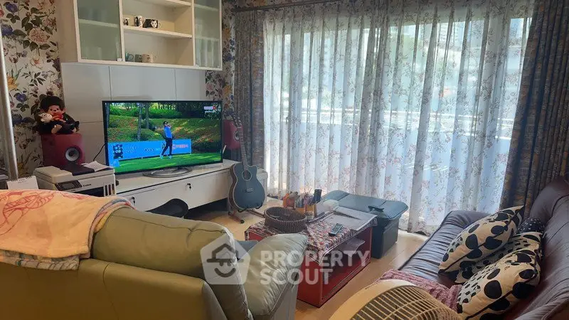 Cozy living room with floral curtains, modern TV setup, and comfortable seating.