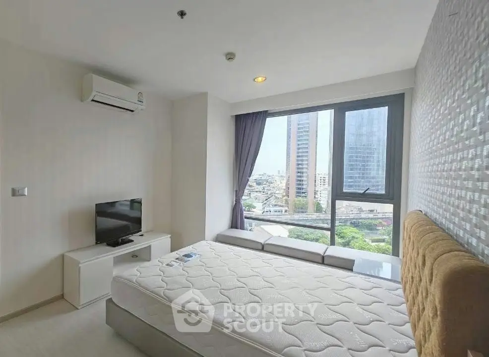 Modern bedroom with city view, featuring a cozy bed, TV, and air conditioning.