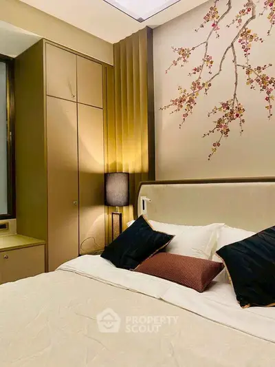 Luxurious bedroom with elegant decor and cherry blossom wall art, featuring plush bedding and ambient lighting.