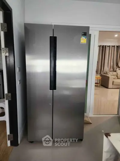 Modern stainless steel refrigerator in a sleek kitchen setting with open layout.