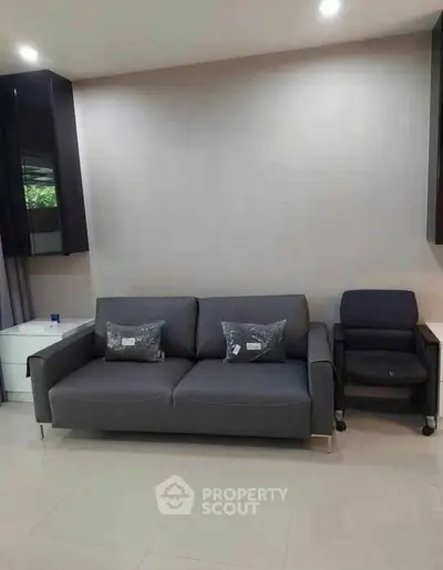 Modern living room with sleek gray sofa and armchair, perfect for stylish comfort.