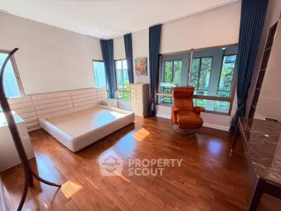 Spacious bedroom with hardwood floors and large windows offering natural light.