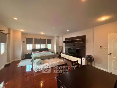 Spacious bedroom with modern entertainment unit and elegant wooden flooring