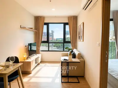 Bright and modern living room with large window and cozy furnishings in a stylish apartment.