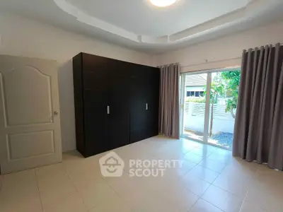 Spacious bedroom with large wardrobe and sliding glass doors to garden view.