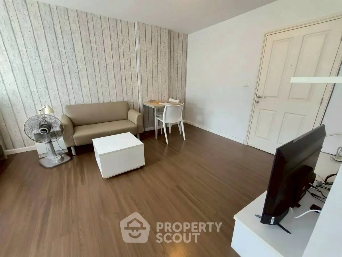 Modern living room with wood flooring, sofa, and TV setup