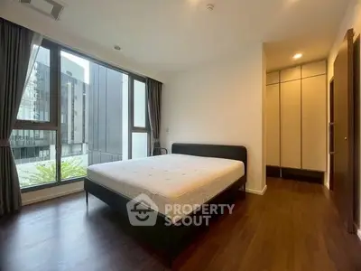 Modern bedroom with large windows and wooden flooring in a stylish apartment.