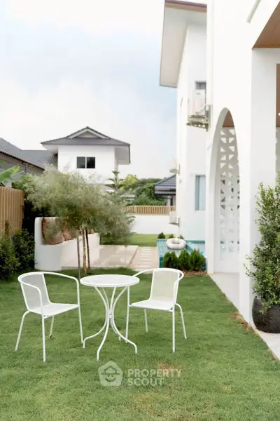 Charming garden with white patio furniture and lush greenery in a modern home setting.