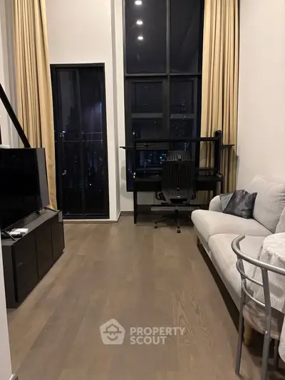 Modern living room with high ceilings and city view, featuring a cozy sofa and sleek TV setup.