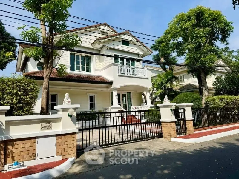 Charming two-story house with lush garden and gated entrance in serene neighborhood.