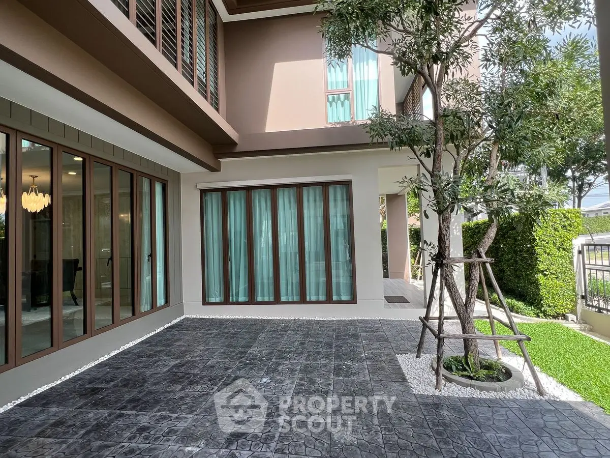 Modern home exterior with spacious patio and lush greenery, perfect for outdoor relaxation.