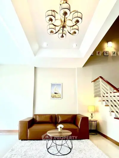 Elegant living room with modern chandelier and stylish brown sofa