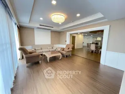 Spacious living room with elegant furniture and chandelier, open layout to dining area, perfect for entertaining.