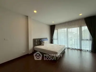 Spacious bedroom with large windows and elegant curtains in modern apartment.