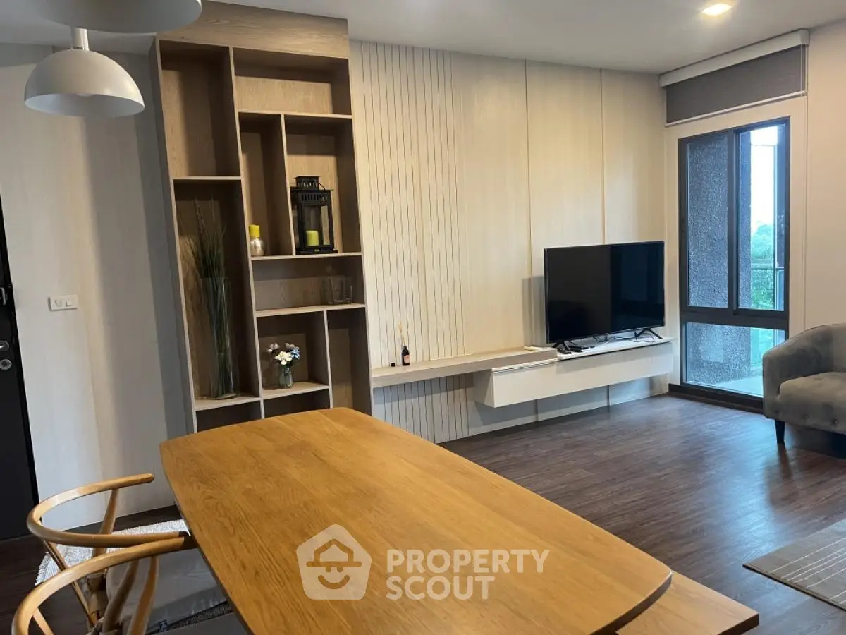 Modern living room with stylish furniture and large TV, featuring wooden flooring and elegant decor.