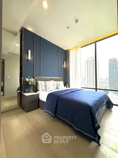 Luxurious bedroom with city view, elegant blue accents, and floor-to-ceiling windows.