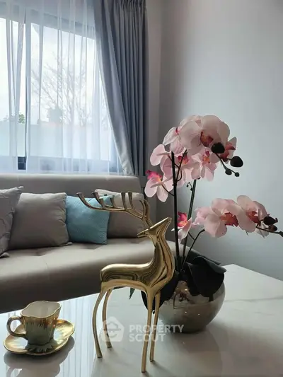 Elegant living room with plush sofa, decorative deer statue, and orchid centerpiece by a sunlit window.