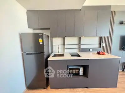 Modern kitchen with sleek cabinetry, built-in microwave, and stainless steel fridge in a compact layout.