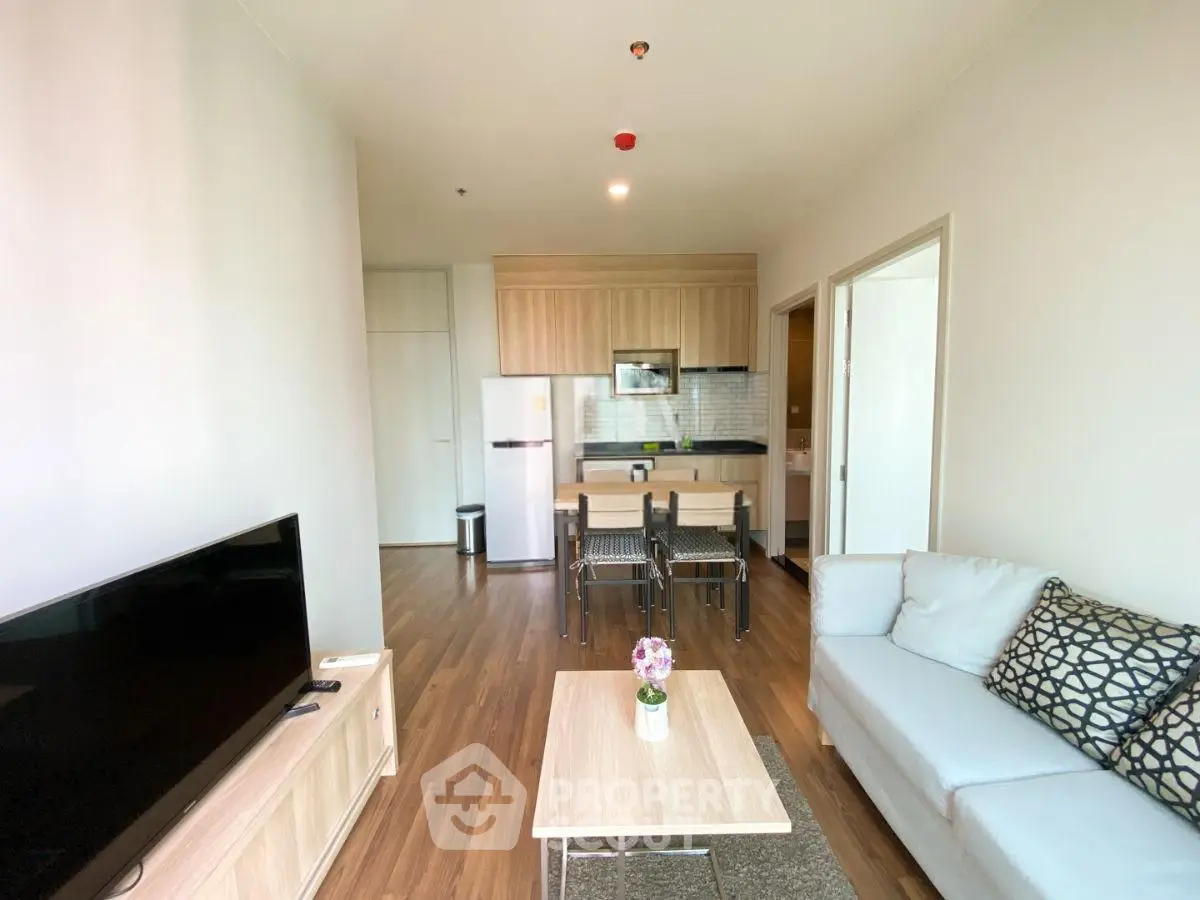 Modern living room with open kitchen, stylish furniture, and natural light.