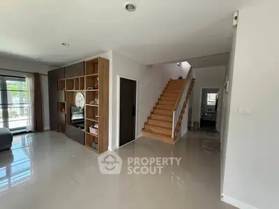 Spacious modern living area with sleek staircase and built-in shelving, perfect for stylish family living.
