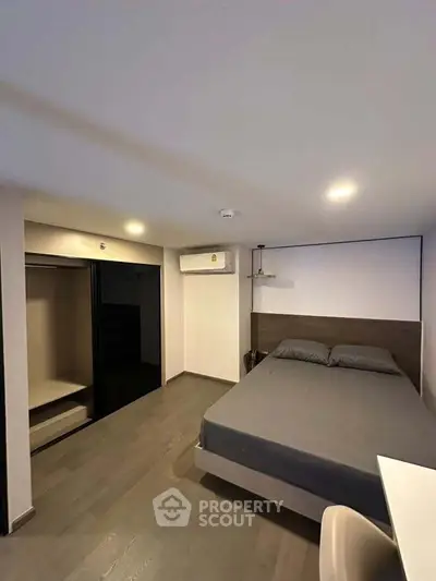 Modern bedroom with sleek design, featuring a comfortable bed, built-in wardrobe, and air conditioning.