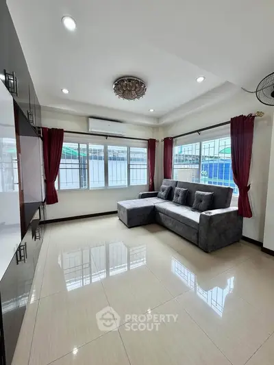 Spacious living room with modern sofa and large windows, perfect for natural light.