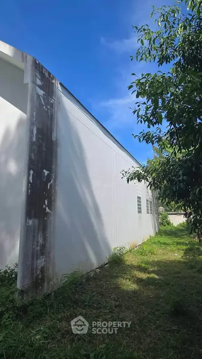 Exterior view of a white building with lush greenery and blue sky.