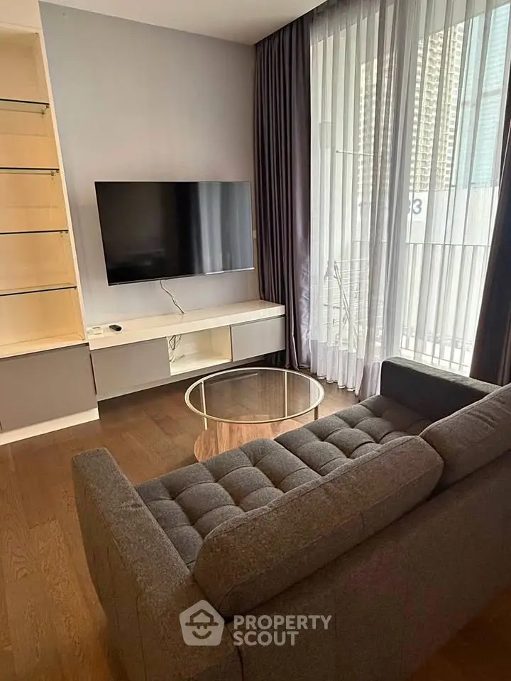 Modern living room with sleek TV setup and stylish furniture in a high-rise apartment.
