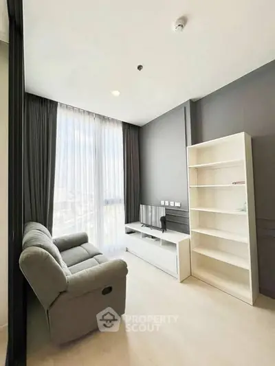 Modern living room with sleek furniture and large window offering natural light.