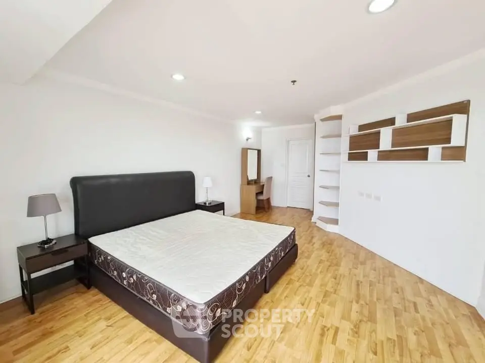 Spacious bedroom with modern furnishings and wooden flooring in a stylish apartment.