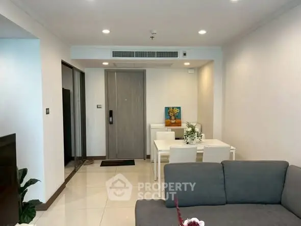 Modern living room with dining area, featuring sleek furniture and bright lighting.