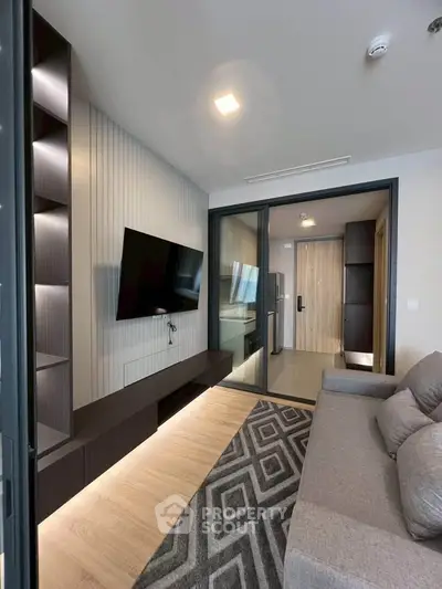 Modern living room with sleek design, featuring a wall-mounted TV, stylish shelving, and a cozy gray sofa.