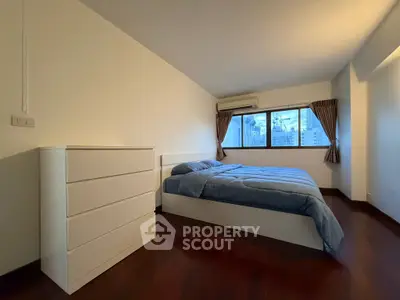 Spacious bedroom with city view, featuring a modern bed and dresser, perfect for urban living.