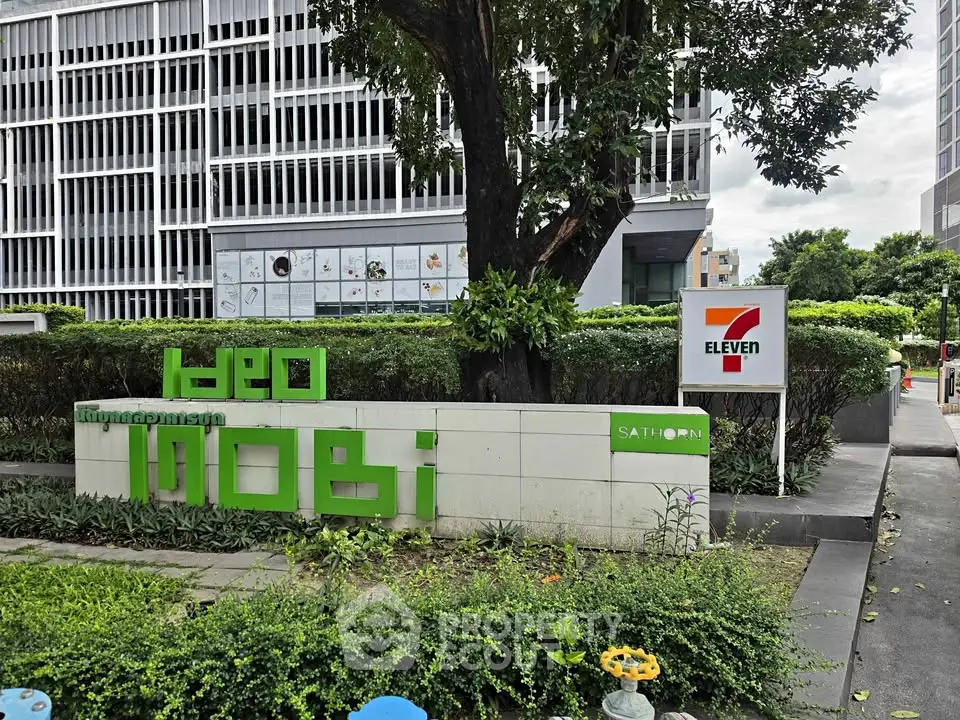 Modern building exterior with lush greenery and prominent signage in urban setting.