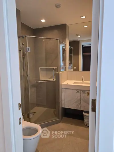 Modern bathroom with glass shower and sleek vanity in luxury apartment.
