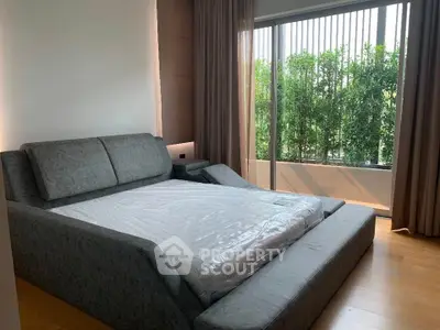 Luxurious bedroom with modern bed and large window overlooking greenery, perfect for relaxation.