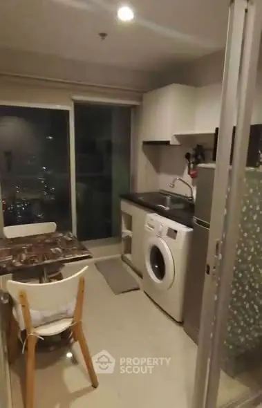 Cozy kitchen with washing machine and dining area in modern apartment