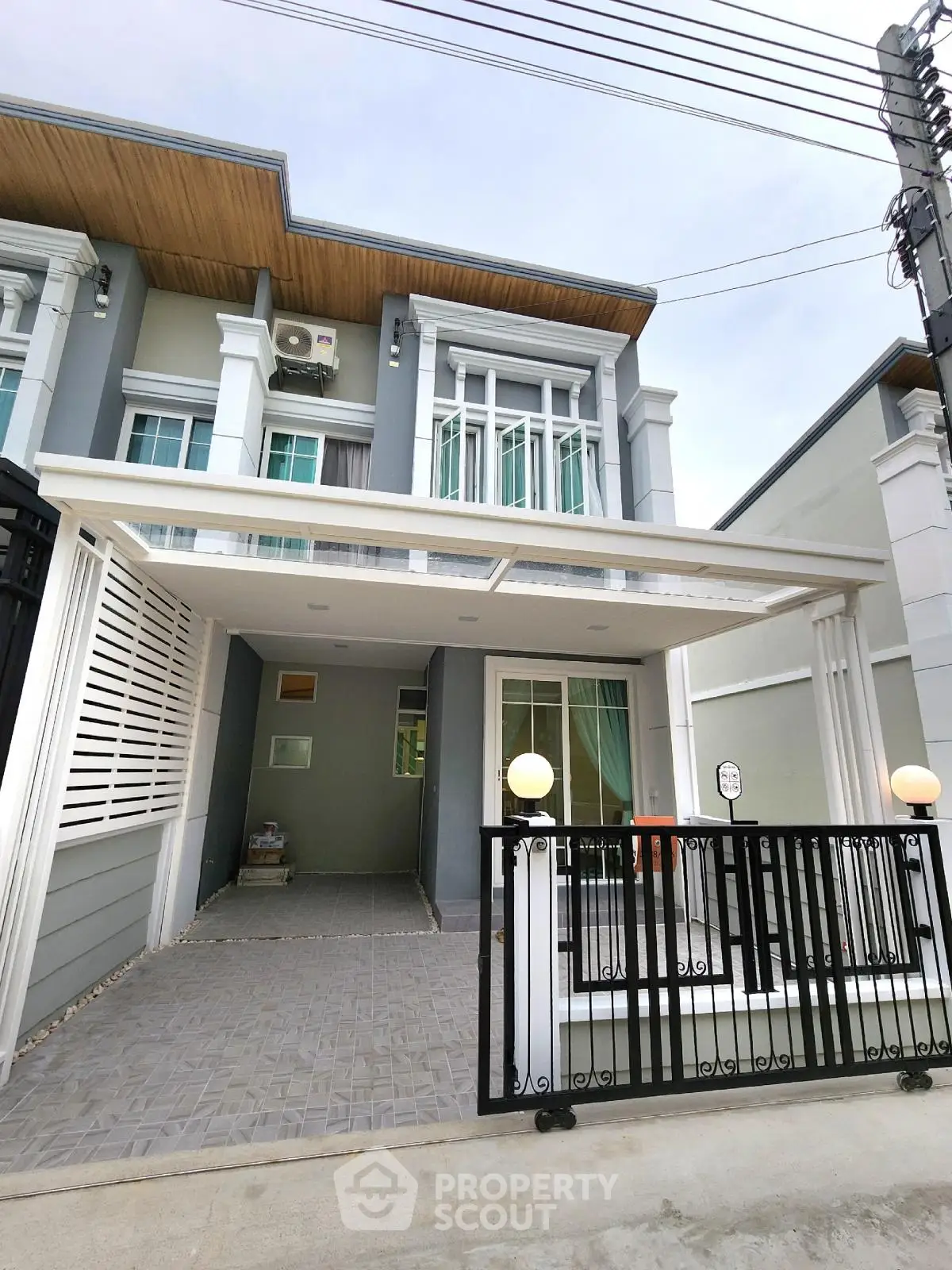 Modern townhouse exterior with gated entrance and covered parking area