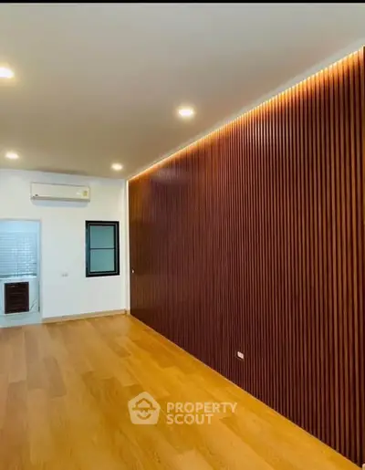 Modern living room with wooden accent wall and recessed lighting
