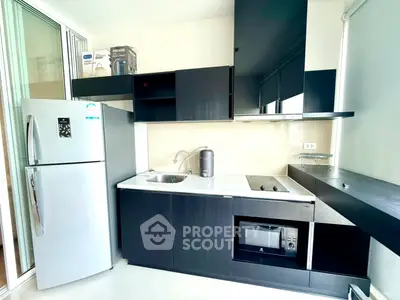 Modern kitchen with sleek black cabinetry and stainless steel appliances in a contemporary apartment.