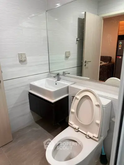 Modern bathroom with sleek fixtures and large mirror in a contemporary apartment.