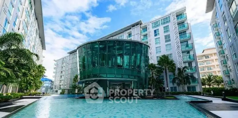 Luxurious modern apartment complex with stunning glass architecture and inviting pool area.