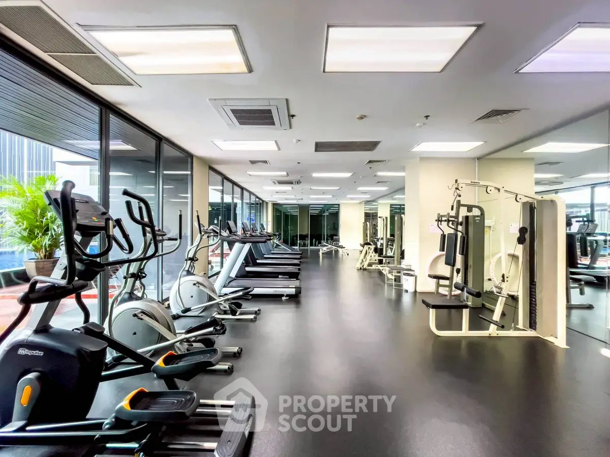 Spacious modern gym with state-of-the-art equipment and large windows for natural light.