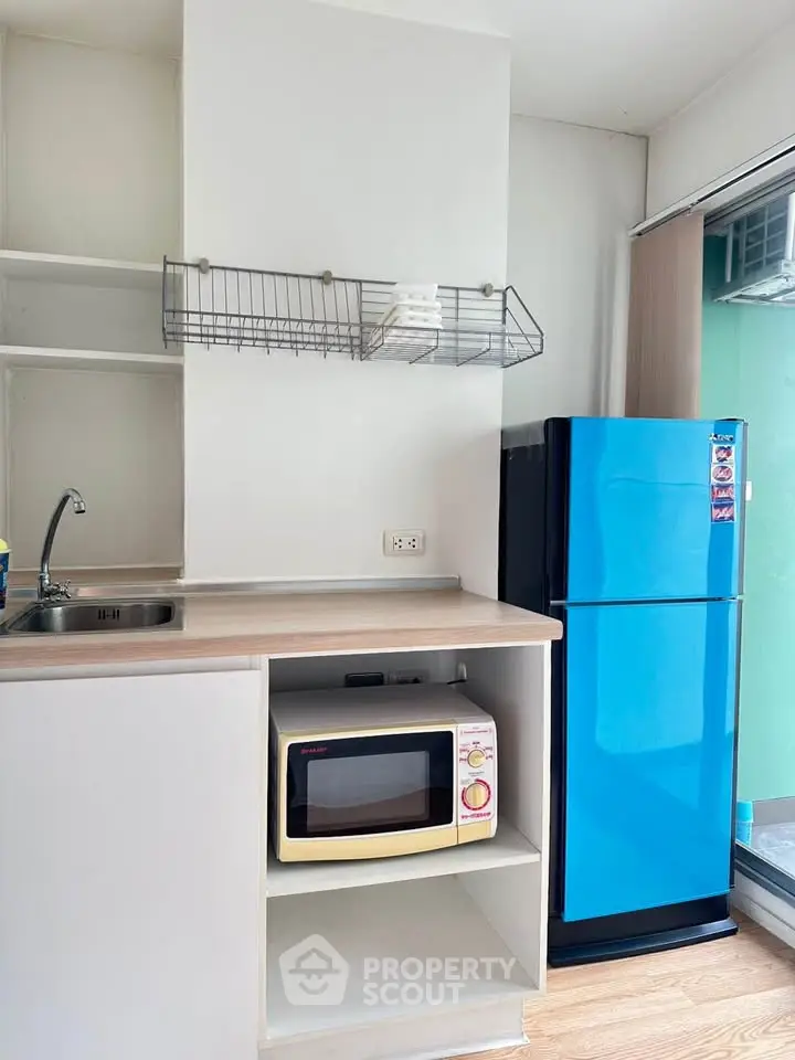 Compact kitchen with blue fridge and microwave in modern apartment