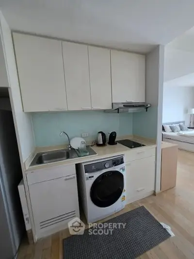 Compact modern kitchen with integrated washing machine and sleek cabinetry in a cozy apartment setting.