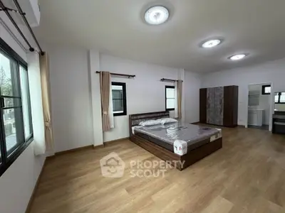 Spacious modern bedroom with wooden flooring and ample natural light