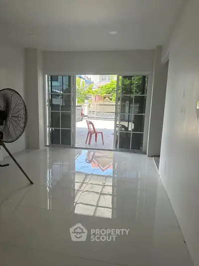 Spacious living room with large sliding glass doors opening to a patio, featuring glossy tiled floors.