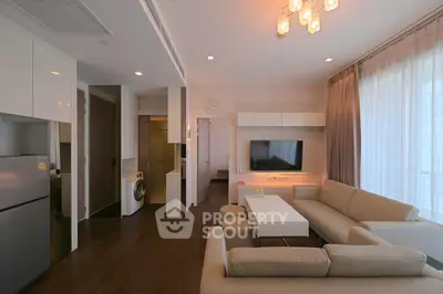 Modern living room with elegant furniture and open kitchen layout, featuring a washing machine and stylish lighting.